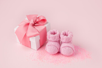 Pair of small pink baby socks and gift box on pink background with copy space for your warm message, baby shower, first newborn party background, copy space, monochrome