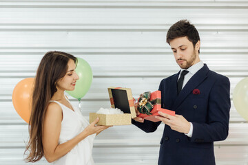 Young Caucasian couple celebrating new year together, exchanging gifts to each other.