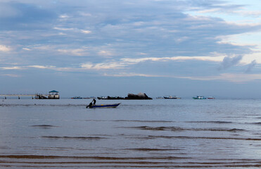 Fototapeta na wymiar View of dawn at the seaside with a man start the engine on a boat, Tioman Island