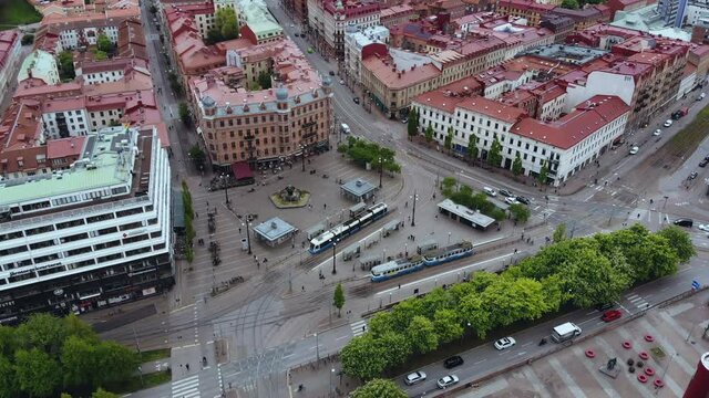 Blue Tram And Cars Driving At The Jarntorget Public Square Surrounded By The Red Roof Buildings In Gothenburg, Sweden. - aerial drone