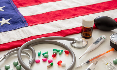 US health. Medical instruments and pills on a USA flag, closeup view.