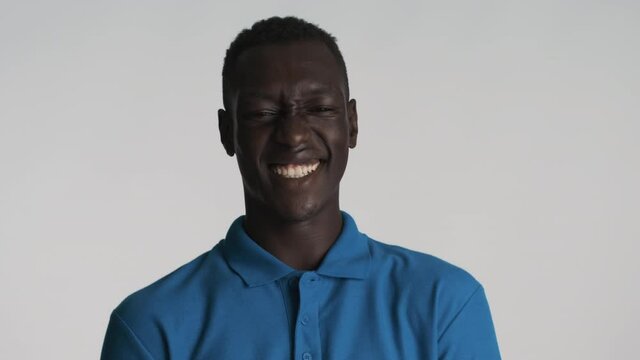 Attractive cheerful African American guy joyfully showing tongue on camera and laughing over gray background. Happy expression