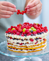 Pastry chef decorates cake with fresh red currant berries