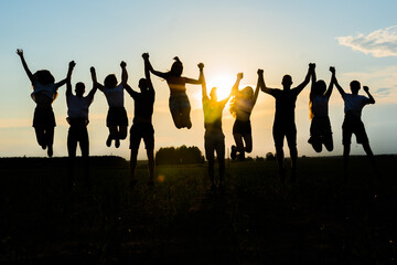 Silhouettes of jumping friends on a sunset background.
