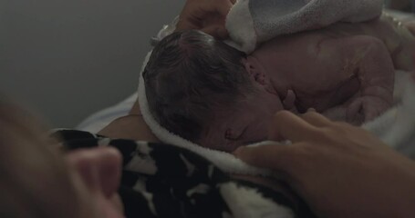 Young woman holding her newbown baby after giving birth in hospital