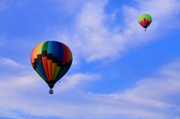 Two multicolored balloons in rise high into the sky