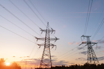 Fototapeta premium High-voltage power lines at sunset or sunrise. High voltage electric transmission tower