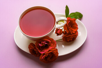 Herbal tea in a cup with red roses
