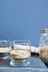 Raw oatmeal in a glass on a blue background with copy space