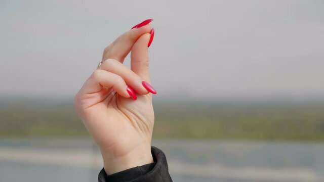 Close up woman hand with red nail polish outdoors. 4K slow motion footage