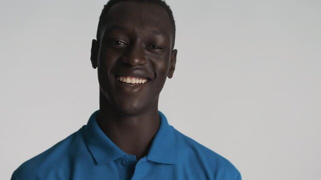 Handsome smiling African American guy confidently showing call me gesture on camera over gray background. Phone gesture