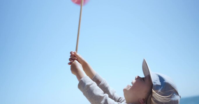 Preschooler boy playing with toy windmill on the beach