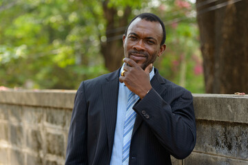 Portrait of handsome bearded African businessman outdoors