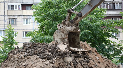 A pile of excavated soil with an excavator bucket lying on it