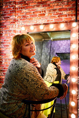 Fat plump charming cute woman with blonde hair in beautiful dress in the room with mirrow and red...