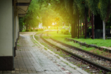 Blurred image of empty railroad track going into the light. Railway tracks with sleepers with platform in the rural station.