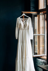 Wedding interior.  The brides dress hangs near the window. Vintage style. Bridal morning details.