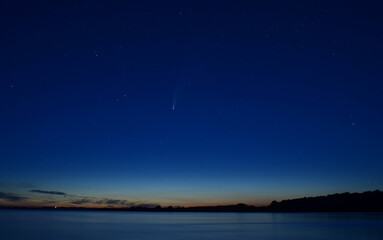 Fototapeta na wymiar View over a lake at midnight with comet Neowise in the sky