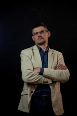 serious actor in glasses with crossed arms on chest looks upwards posing at audition against stage...
