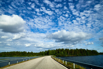 Beautiful landscape with blue sky, white clouds, water of lake and the road that goes to the...