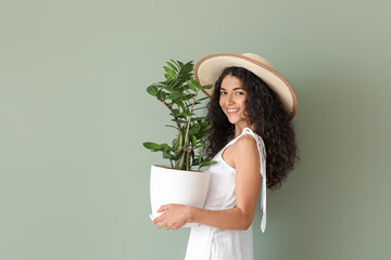 Beautiful young woman with houseplant on color background
