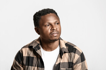 Obraz premium Thoughtful african american man in plaid shirt looking away, pondering future decisions and business strategy