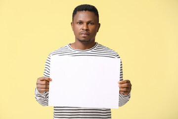 Sad African-American man with poster on color background. Stop racism