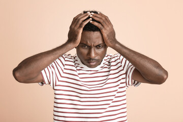 Stressed African-American man on color background. Stop racism