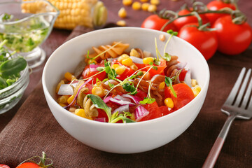 Bowl with tasty pasta salad on table