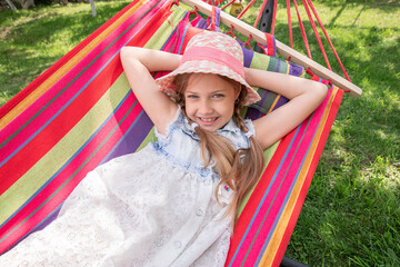 a little girl lying in a hammock on the street in the park