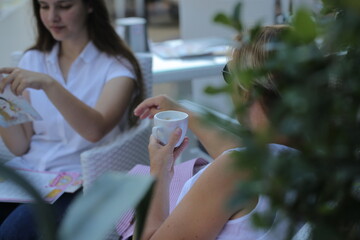 two girls are sitting in a cafe drinking coffee and taking selfies