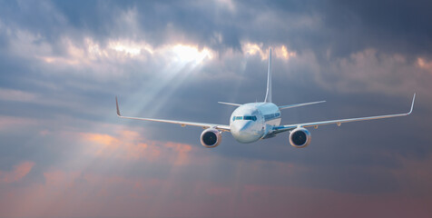 Fototapeta na wymiar Airplane in the sky at sunset and sun rays