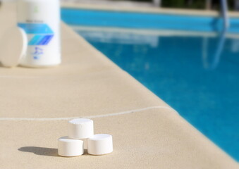 White mini chlorine tablet in the hand of a service worker for disinfection of swimming pools. The beginning of the swimming season is hot summer.