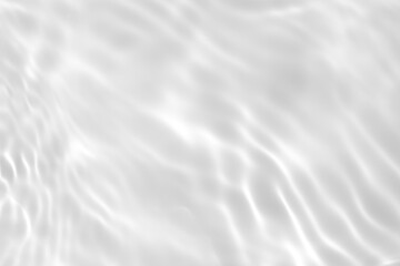 Closeup of desaturated transparent clear calm water surface texture with splashes and bubbles. Trendy abstract nature background. White-grey water waves in sunlight.