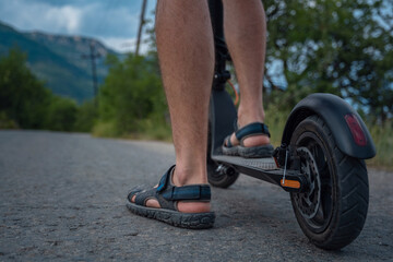 Young man riding an electric scooter on mountain range. Ecological transportation concept