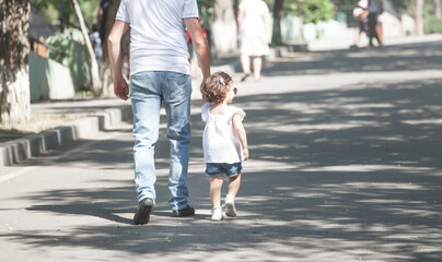 Little daughter and father walking in the park.