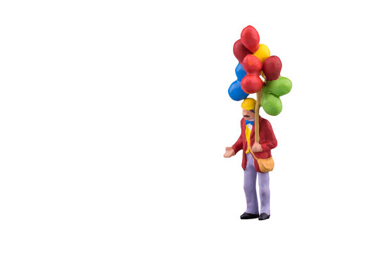 Close Up Of Miniature People With Floating Balloon Isolated With Clipping Path On White Background.