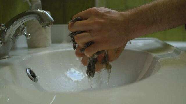 close up shoot mens hands squeezing floor mop in the sink in bathroom