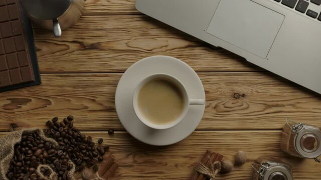 Serving a cup of black coffee with delicious crema by woman's hand. Concept for Coffee break during work in cafe or home. Laptop and coffee background. Horizontal top view