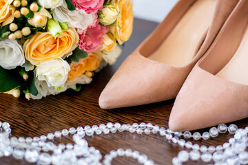 wedding bouquet of roses next to beige bride’s shoes