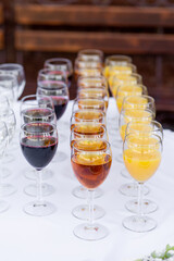 glass wine glasses filled with drinks stand in rows