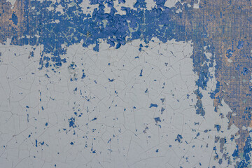 Blue peeling paint on the wall. Old concrete wall with cracked flaking paint. Weathered rough painted surface with patterns of cracks and peeling. High resolution texture for background and design.