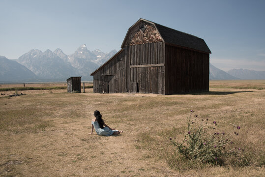 Rear view of teenage girl sitting in front of barn