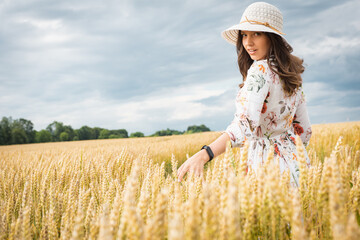 Portrait of a girl in a wheat field. Portrait of a beautiful girl in a white dress and hat on a wheat field. Girl in a white dress and hat. Wheat field. Portrait of a young woman in nature