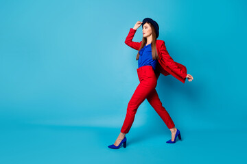 Fototapeta na wymiar Full body profile photo of self-confident pretty business lady boss walking down street wear retro cap red suit blouse blazer pants high-heels isolated blue color background