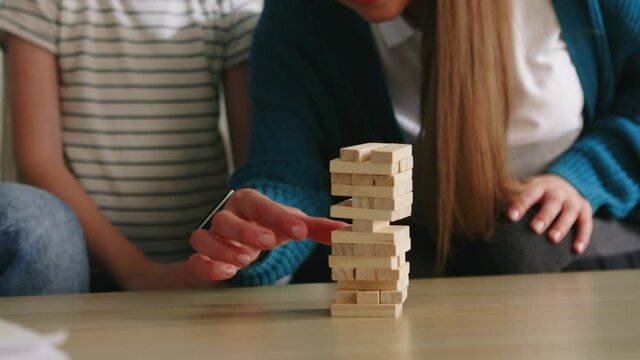 Young parents spend time with their small daughter, reducing stress and playing their favorite board game, jenga, family relationships concept, Foreground, Slow motion.