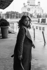 Obraz premium black and white portrait of young smiling happy pretty girl in coat, turtleneck posing outdoors. Street style portrait photo session of attractive female, urban photoshoot of beautiful elegant model