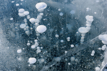 Beautiful ice of Lake Baikal with abstract cracks and frozen air bubbles