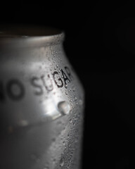 Close up macro image of a can of soda with condensation on the outside set against a black background with space for copy text
