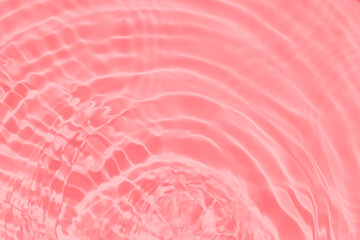 Closeup of pink transparent clear calm water surface texture with splashes and bubbles. Trendy abstract summer nature background. Coral colored waves in sunlight.